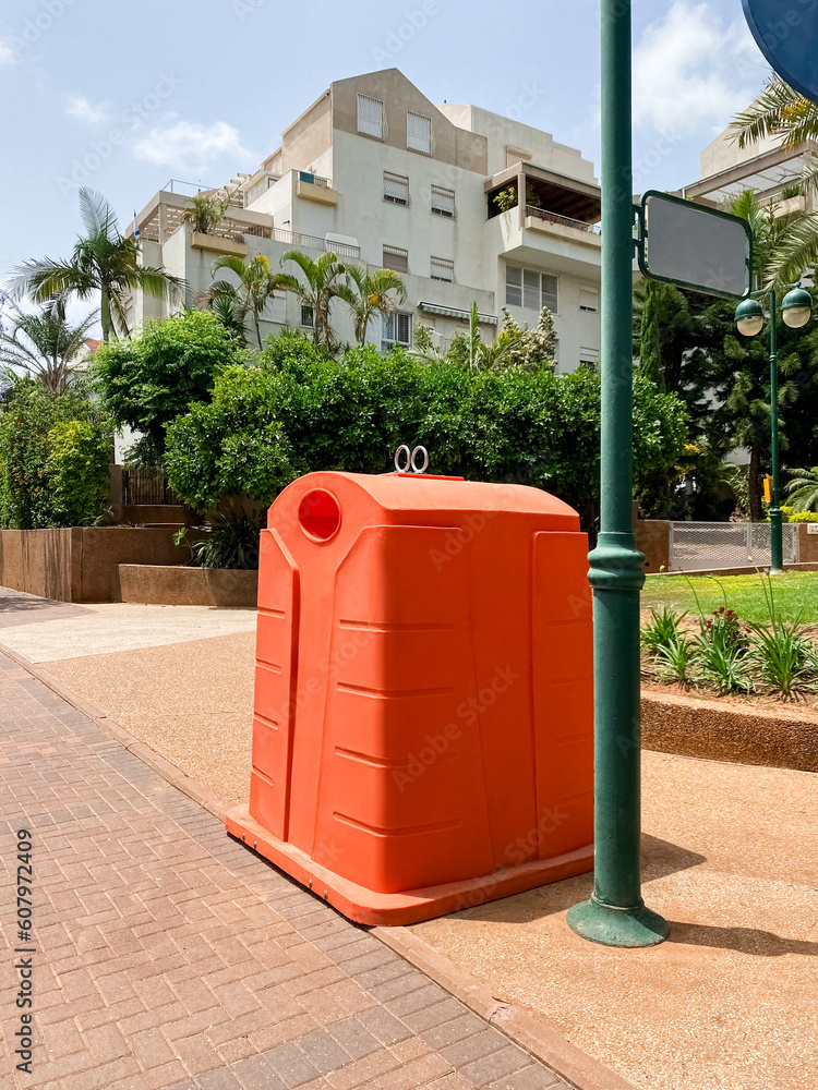 Orange garbage container on city street