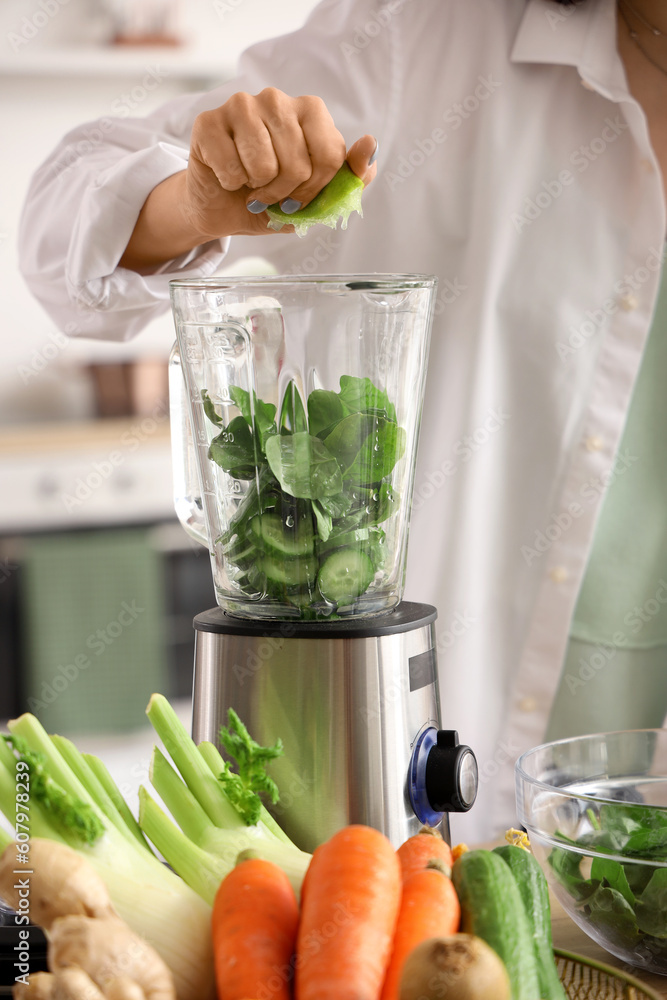Young woman squeezing lime juice into blender in kitchen, closeup