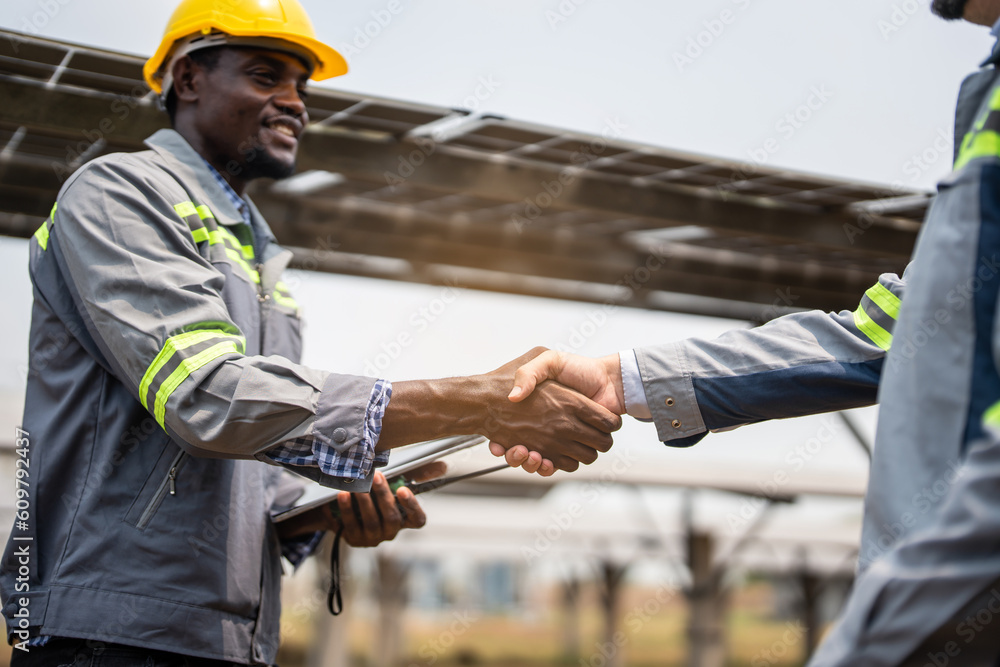 Professional engineer making handshake after work in modern solar farm. 