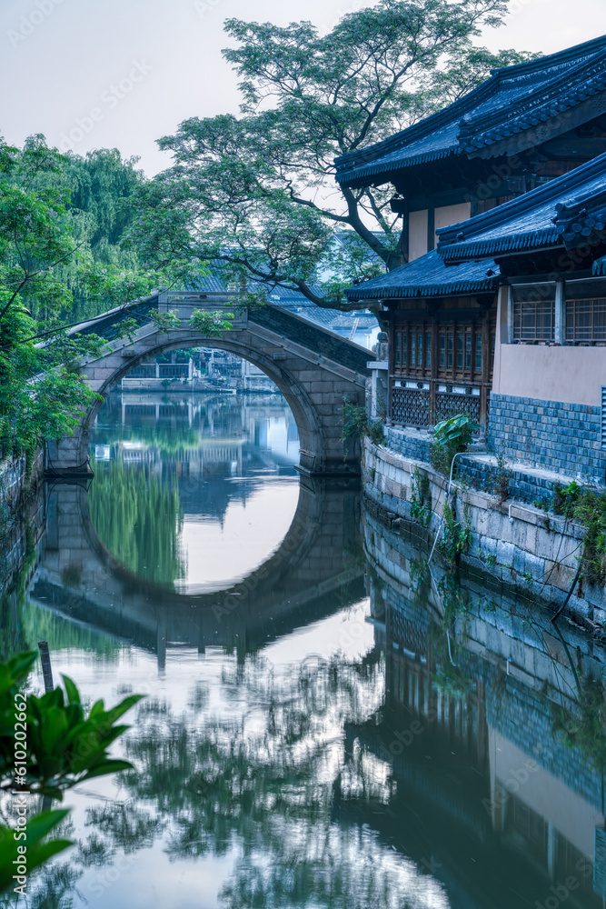 landscape of a Chinese ancient town with river, wooden houses and bridge.