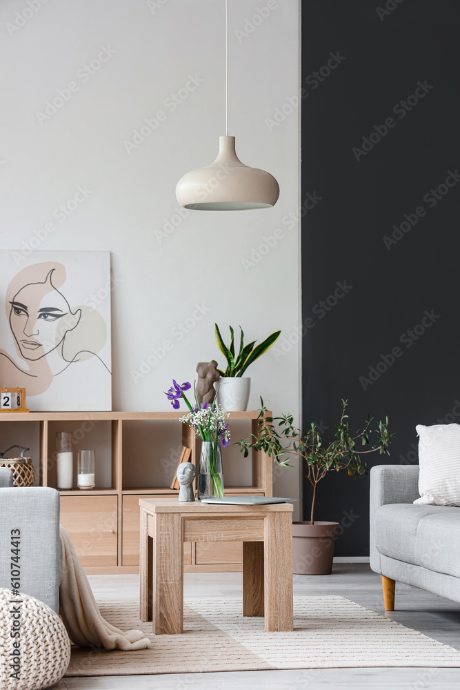 Interior of light living room with grey sofas and iris flowers on wooden coffee table