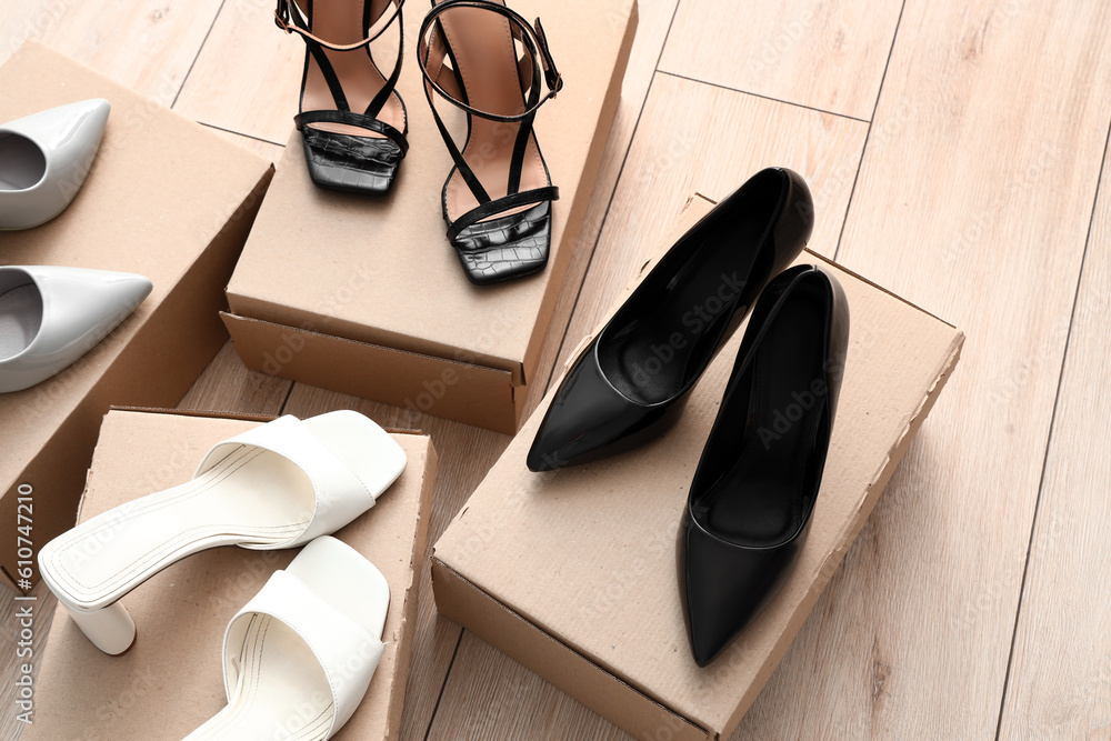 Cardboard boxes with heeled shoes on light wooden background