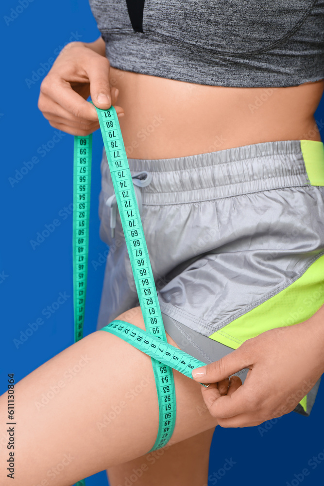 Young woman with measuring tape on blue background, closeup. Diet concept