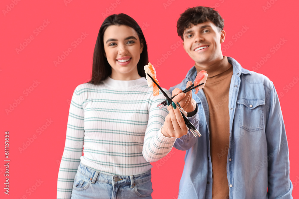 Young couple eating sushi on red background, closeup