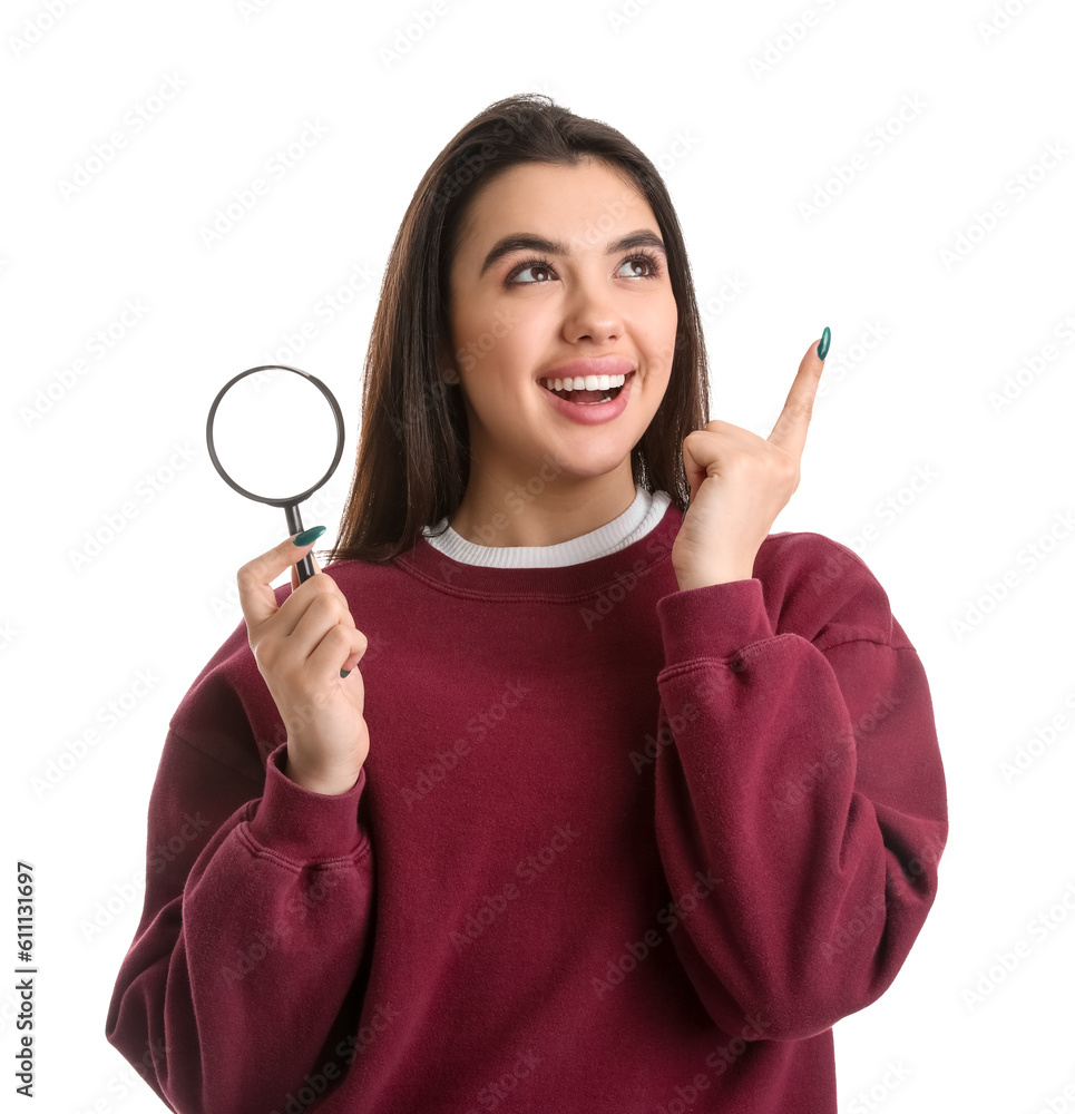 Young woman with magnifier pointing at something on white background