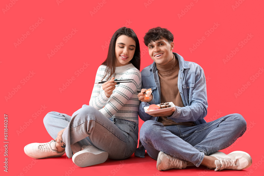 Young couple eating sushi on red background