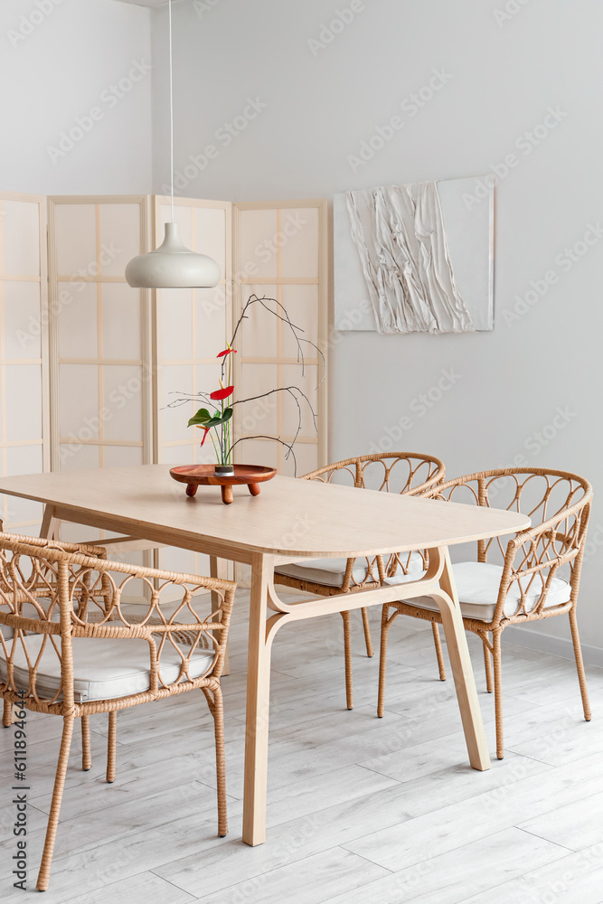 Dining table with beautiful ikebana in interior of room