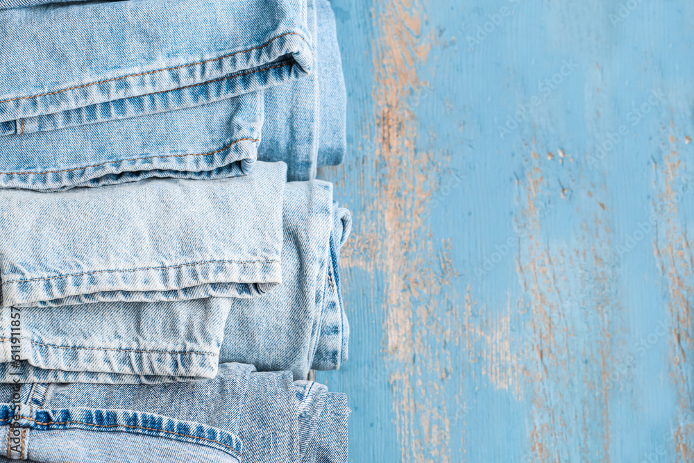 Different rolled jeans on blue wooden background, closeup