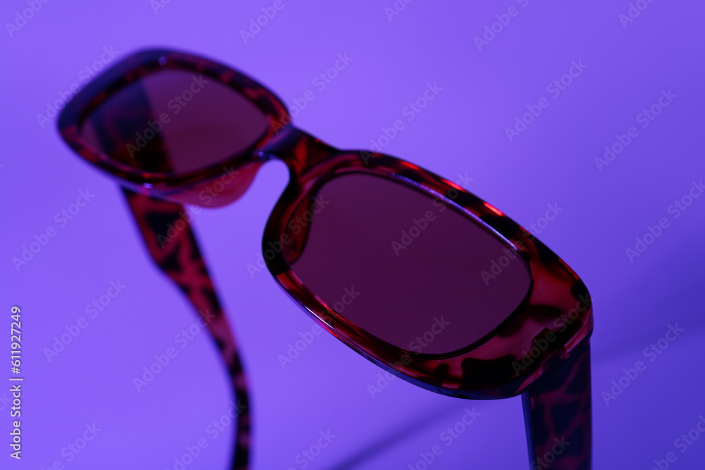 Stylish leopard print sunglasses on purple background