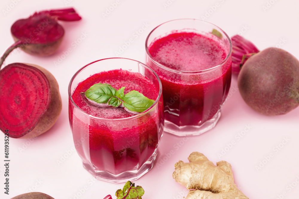 Glasses of healthy beet juice with basil and ginger on pink background