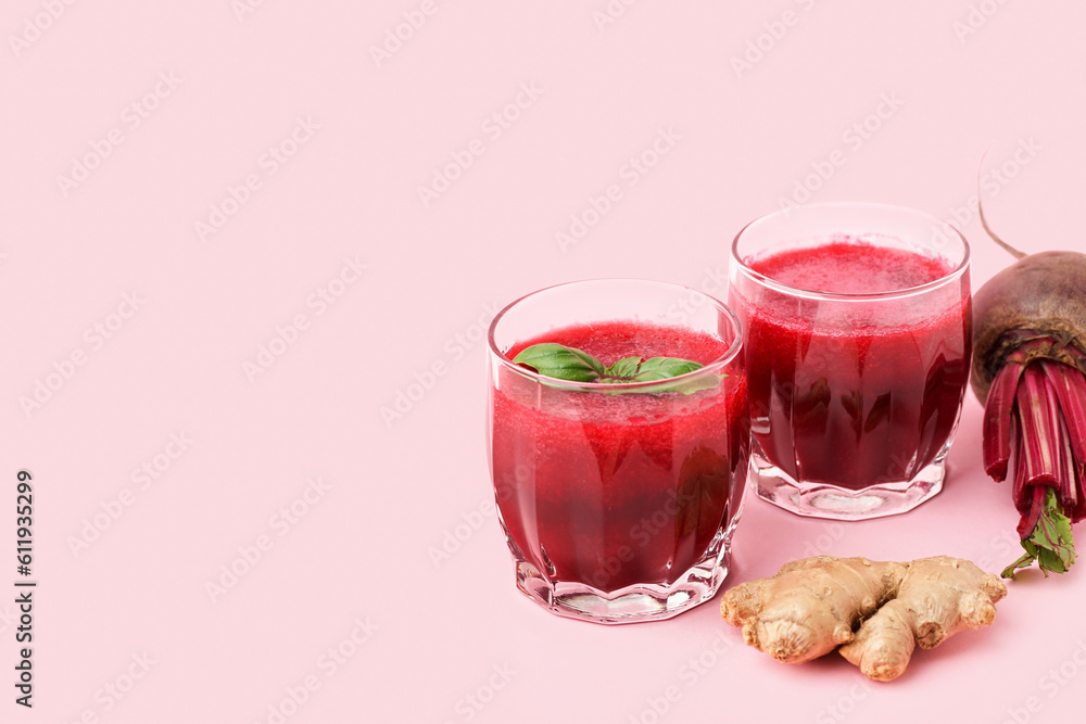 Glasses of healthy beet juice with basil and ginger on pink background