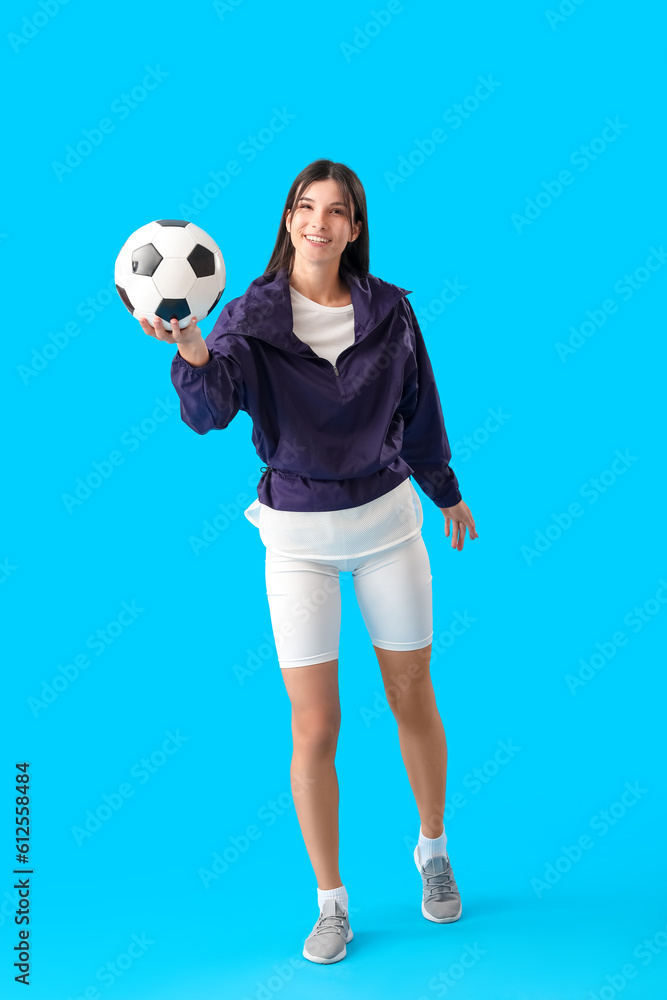 Young woman with soccer ball on blue background