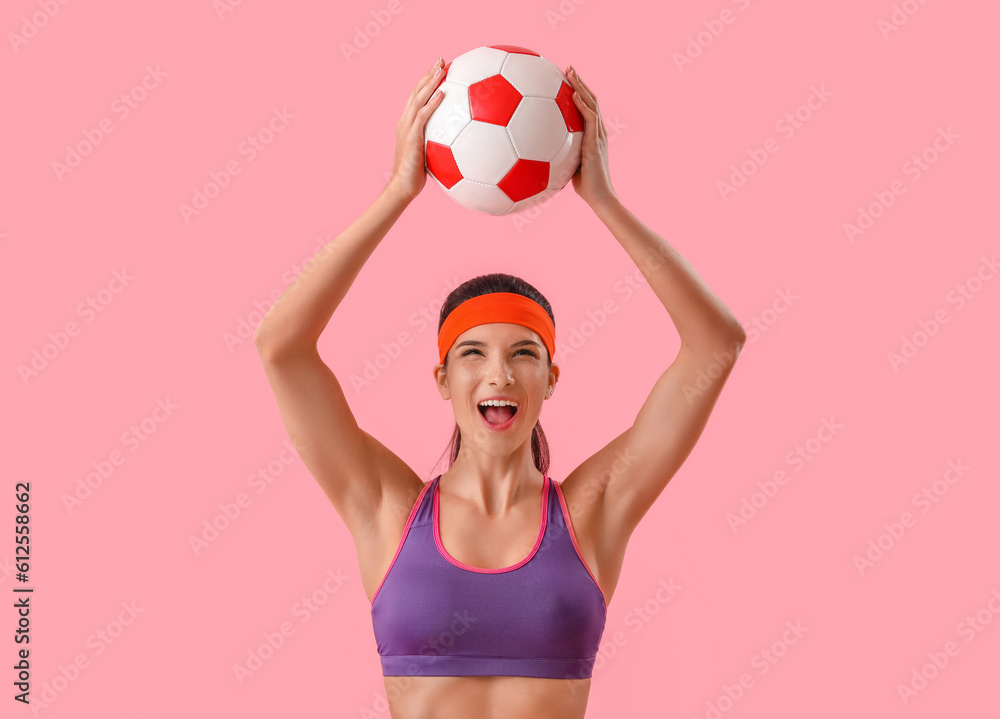 Sporty emotional woman with soccer ball on pink background