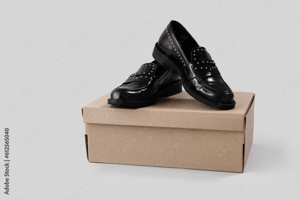 Cardboard box with female classic black shoes on white background