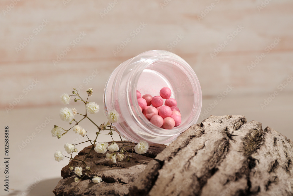 Jar of blush balls, tree bark and gypsophila flowers on light wooden table, closeup