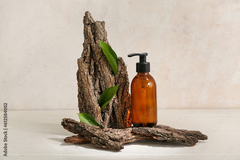 Composition with bottle of cosmetic product, tree bark and plant leaves on light background