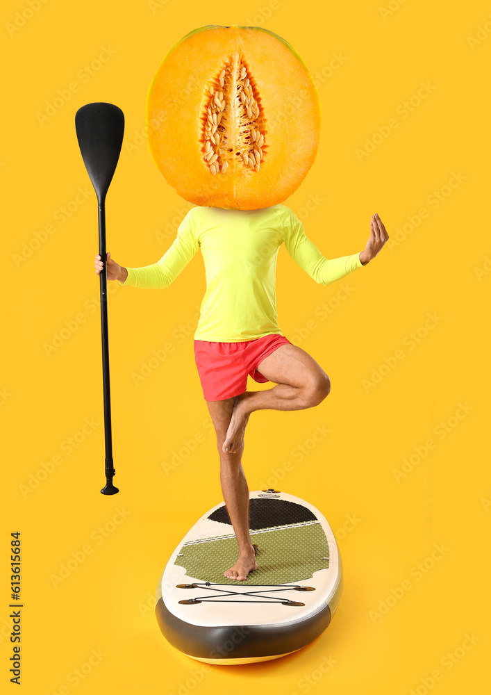 Young man meditating on sup board against color background