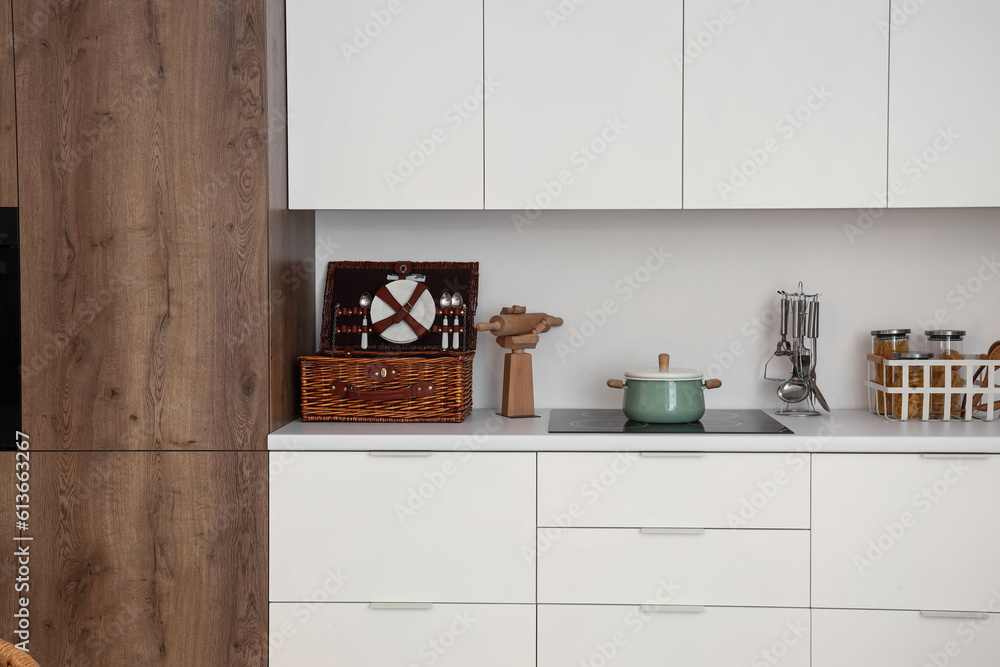 White counters with electric stove, cooking pot and utensils in interior of modern kitchen