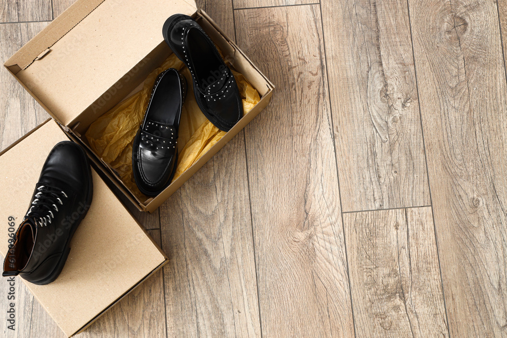 Cardboard boxes with black female shoes on light wooden background