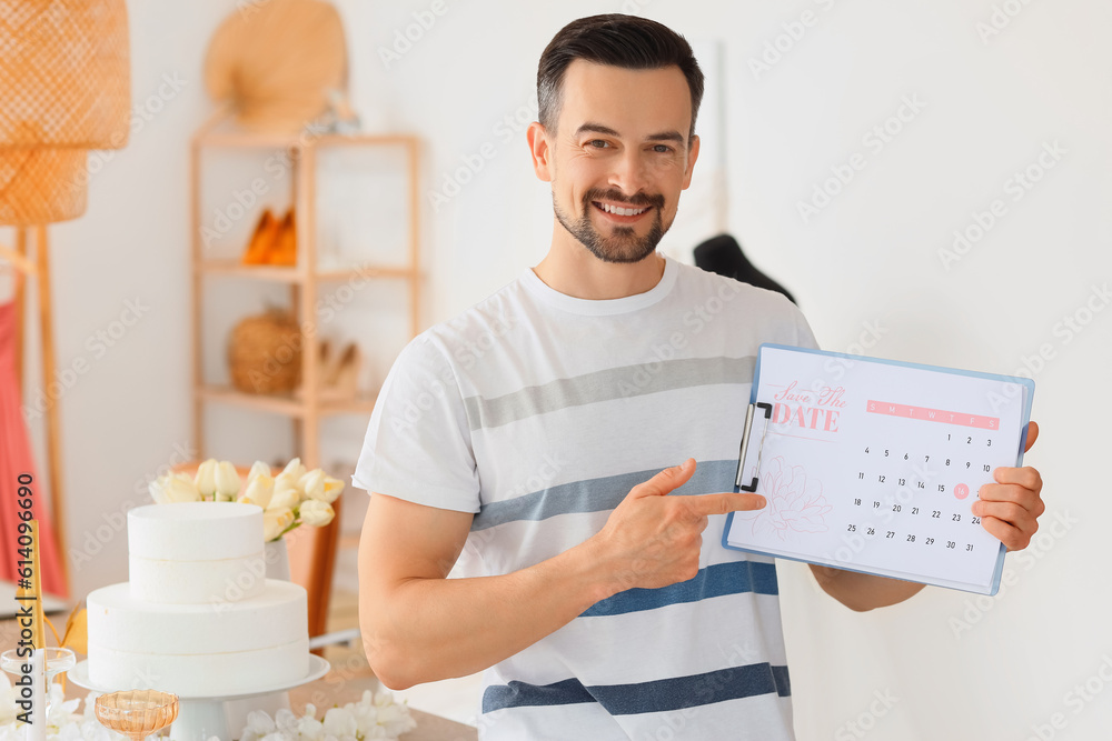 Male wedding planner with Save the Date Announcement in office