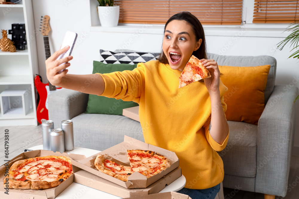 Beautiful woman with tasty pizza taking selfie at home
