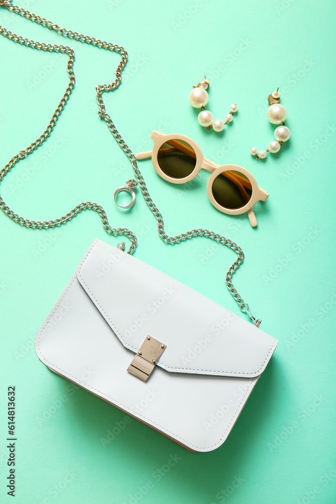 Stylish bag and different accessories on turquoise background