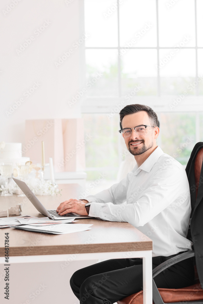 Male wedding planner working with laptop in office
