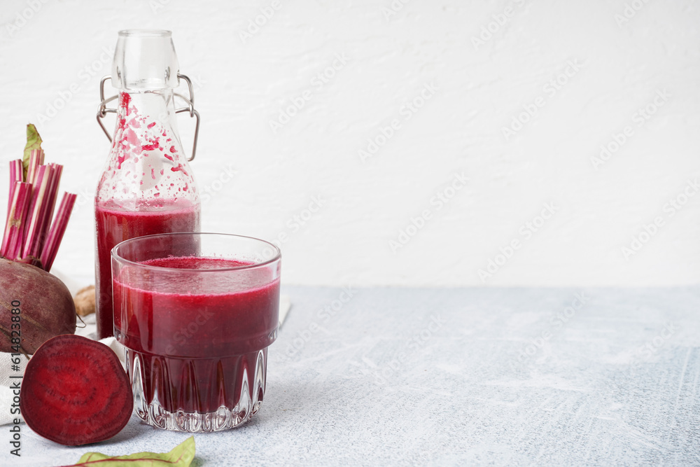 Bottle and glass of fresh beetroot juice on light background