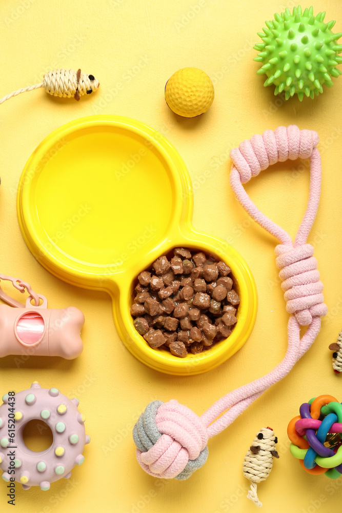 Composition with bowl of wet food and pet care accessories on yellow background