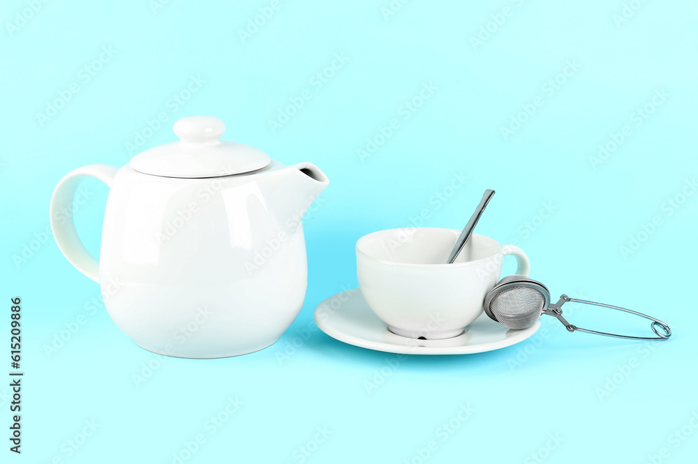Teapot, cup and infuser on blue background