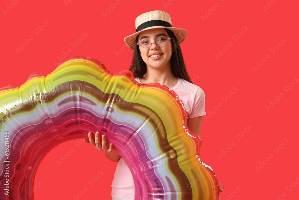 Young woman with inflatable ring on red background