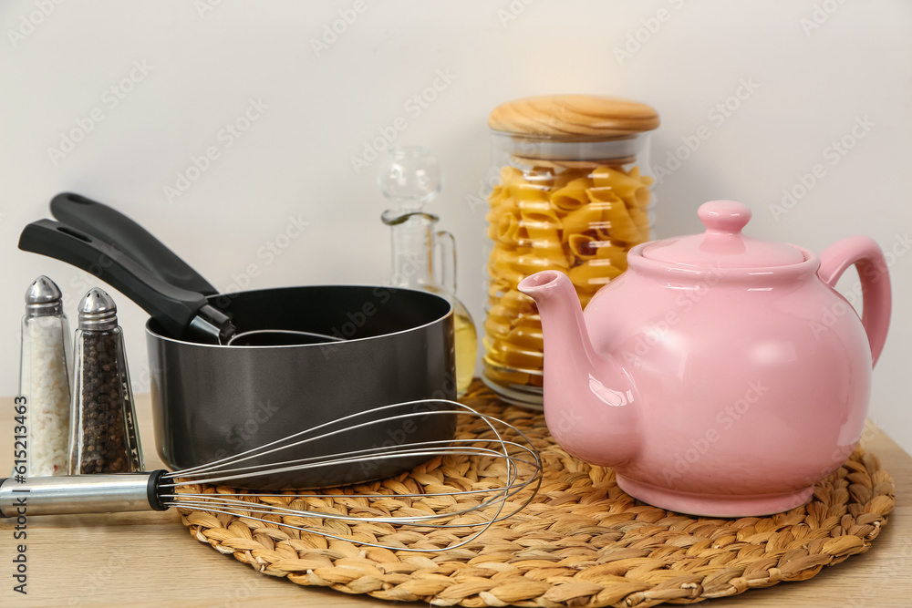 Composition with teapot and different kitchen stuff on white table