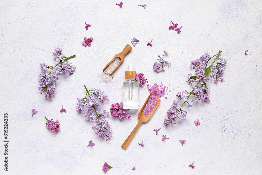 Composition with bottle of lilac essential oil, spoons with sea salt and flowers on light background