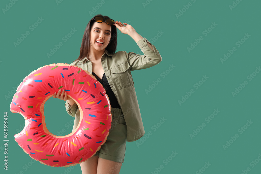 Young woman with inflatable ring on green background