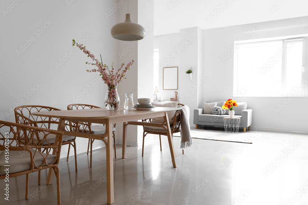 Interior of stylish dining room with blooming sakura branches on table
