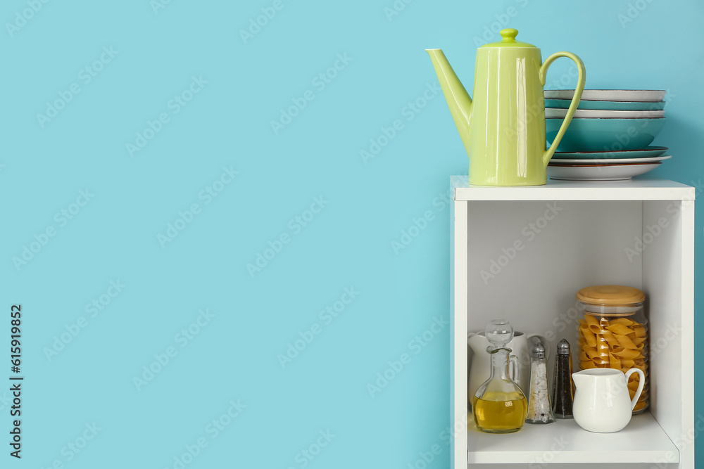 Kitchen shelving with teapot and dishes on blue background
