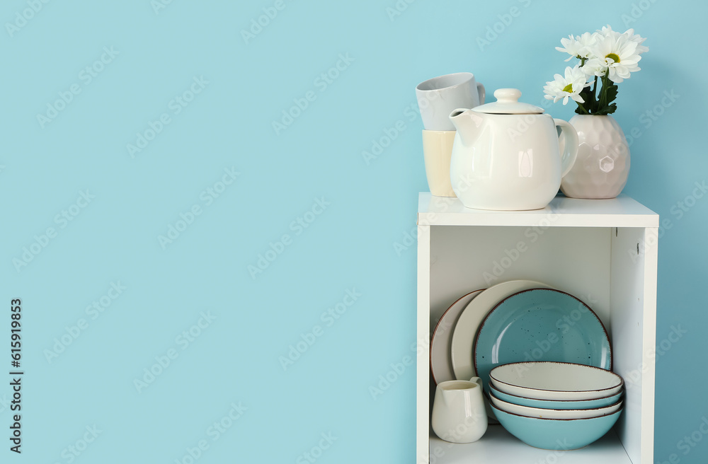 Kitchen shelving with teapot and dishes on blue background