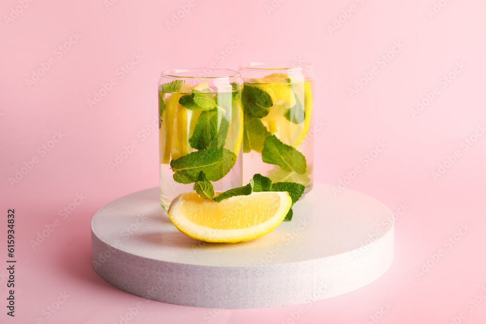 Glasses of infused water with lemon and mint on pink background