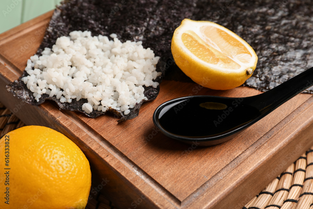 Board of nori with rice, lemon and sauce on table, closeup