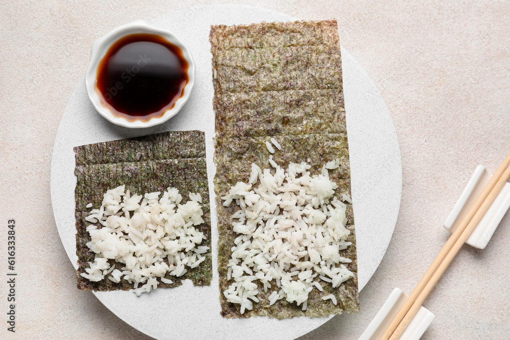 Wooden board of nori with rice and sauce on light background
