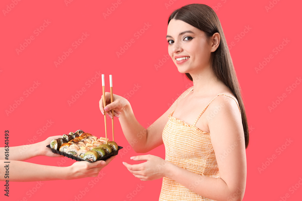 Young woman taking sushi on red background