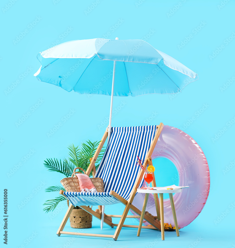Summer composition with beach accessories and cocktail on stool against blue background. Summer vaca