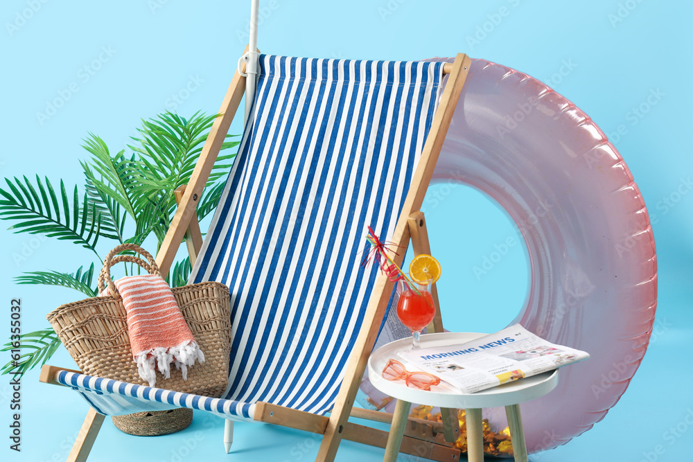 Summer composition with beach accessories and cocktail on stool against blue background. Summer vaca