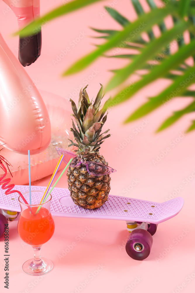 Inflatable ring with cocktail, skateboard and pineapple on pink background. Travel concept
