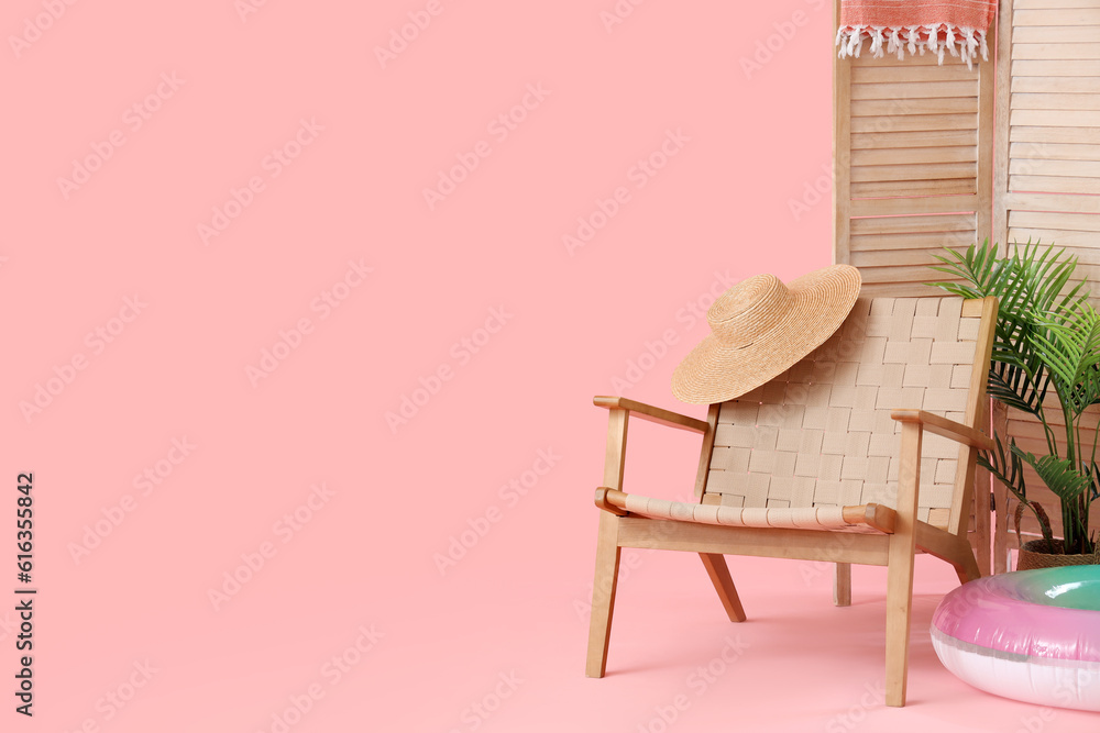 Chair with inflatable ring, wicker hat and folding screen on pink background. Travel concept