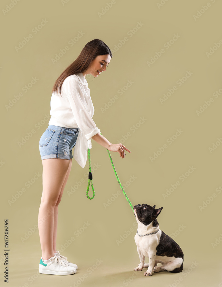 Young woman feeding her French bulldog on green background