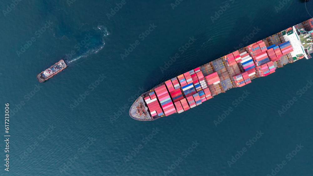 Aerial top view of cargo ship carrying container and running with tug boat for import export goods f
