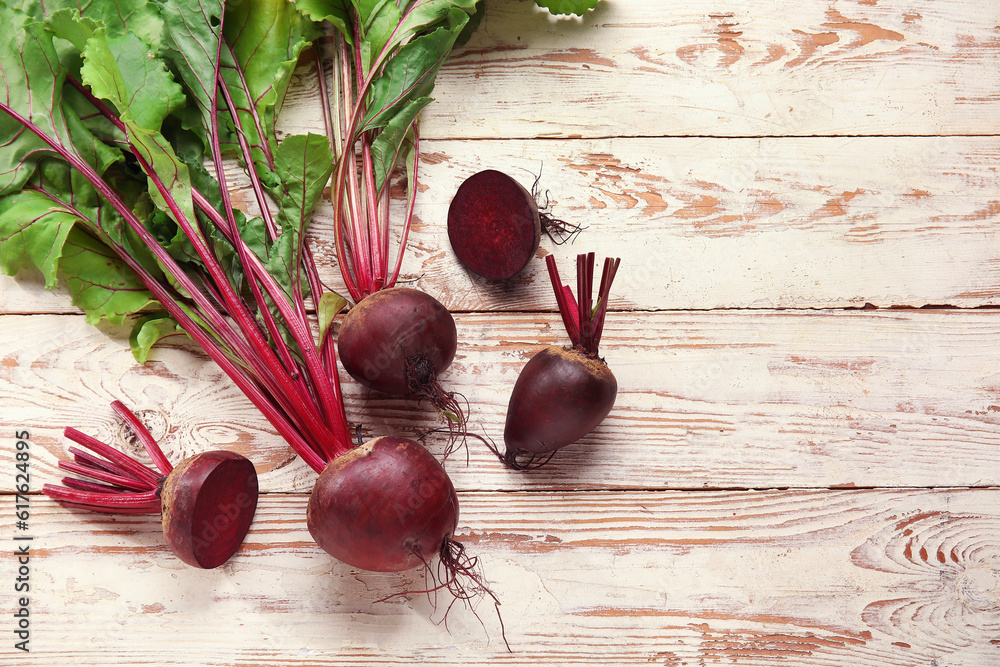 Fresh beets with green leaves on light wooden background