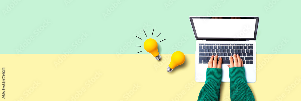 Person using a laptop computer and light bulbs - Flat lay