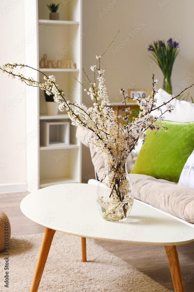 Interior of living room with grey sofa and blossoming tree branches on table
